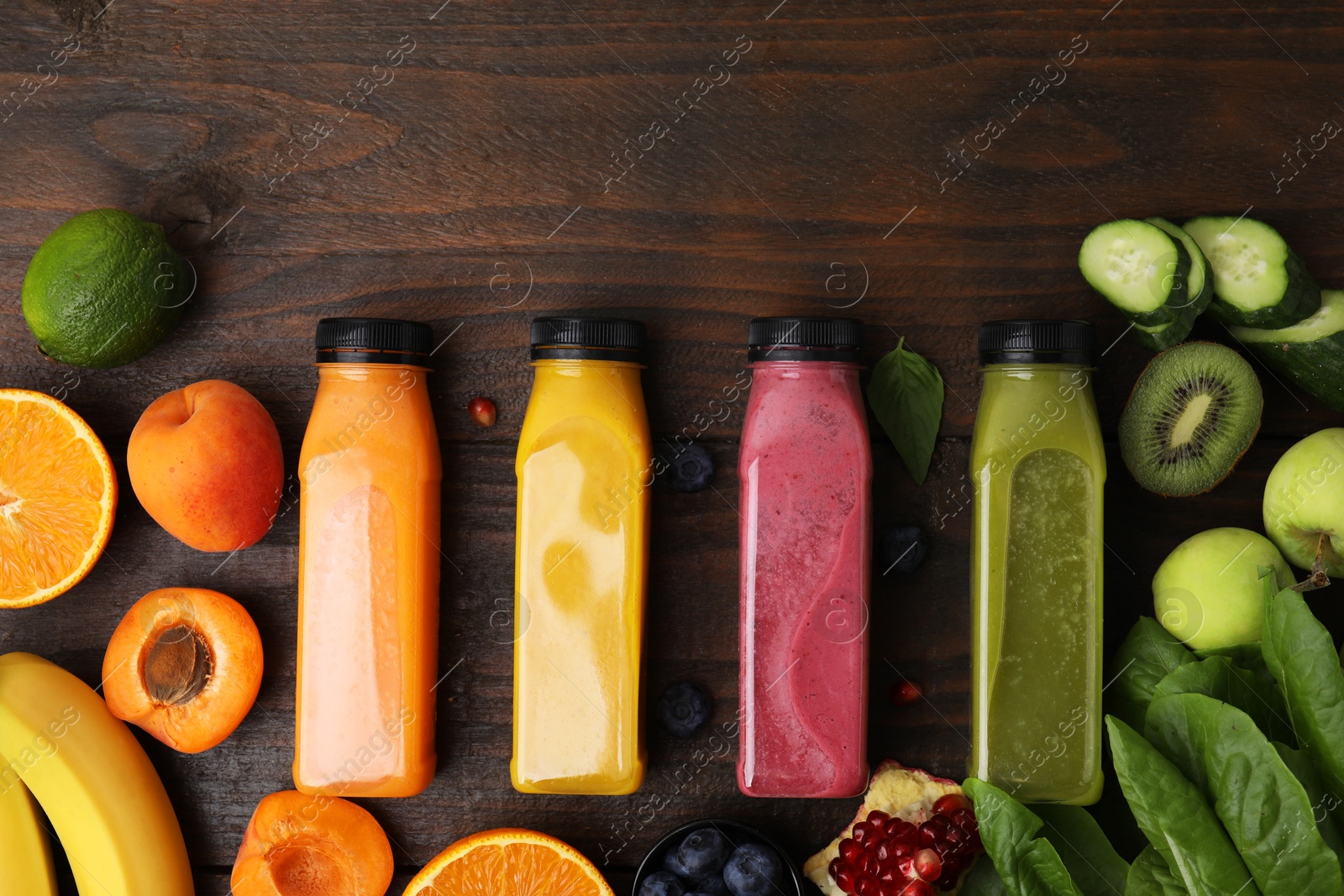 Photo of Glass bottles of tasty smoothies and different products on wooden table, flat lay. Space for text