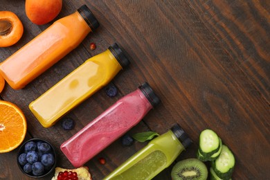 Glass bottles of tasty smoothies and different products on wooden table, flat lay. Space for text