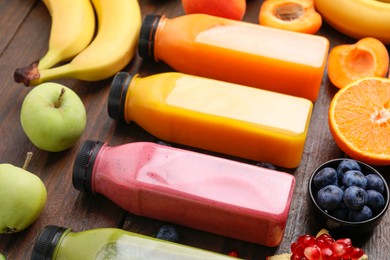 Glass bottles of tasty smoothies and different products on wooden table