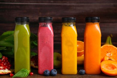 Glass bottles of tasty smoothies and different products on wooden table