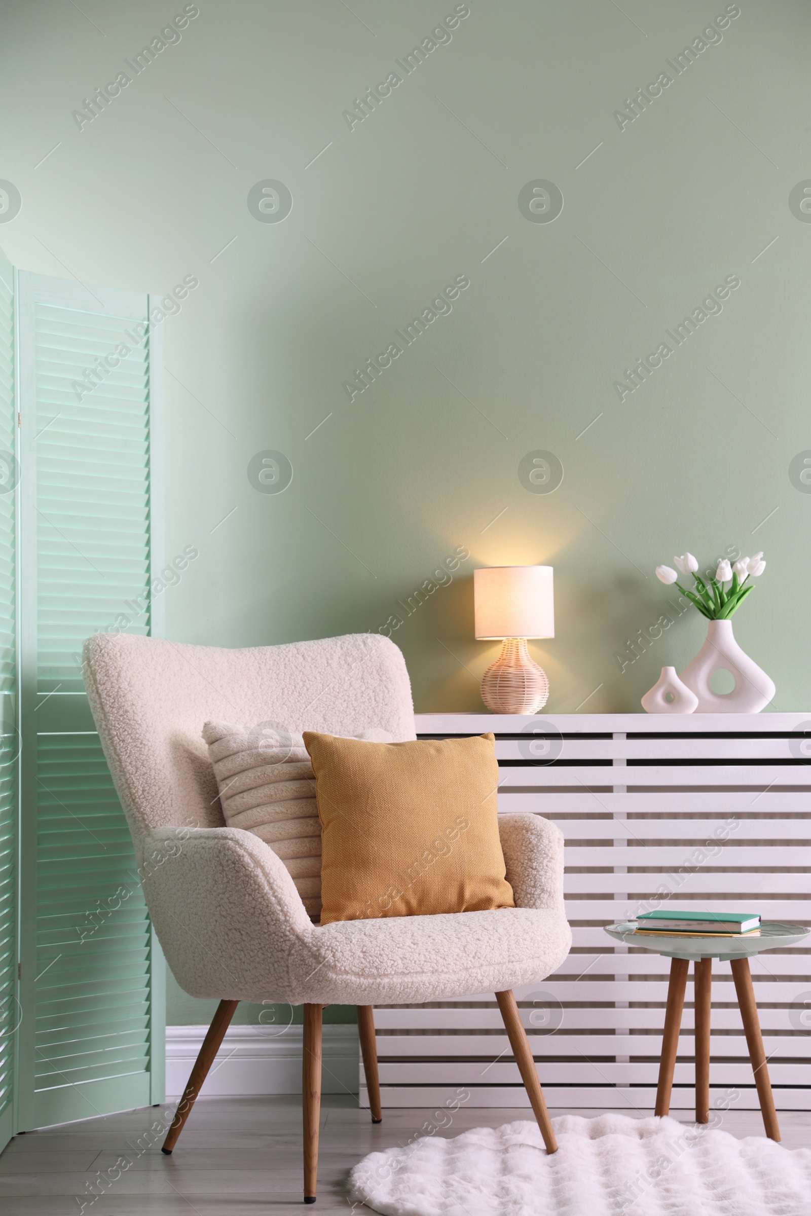 Photo of Two soft pillows on light armchair in living room