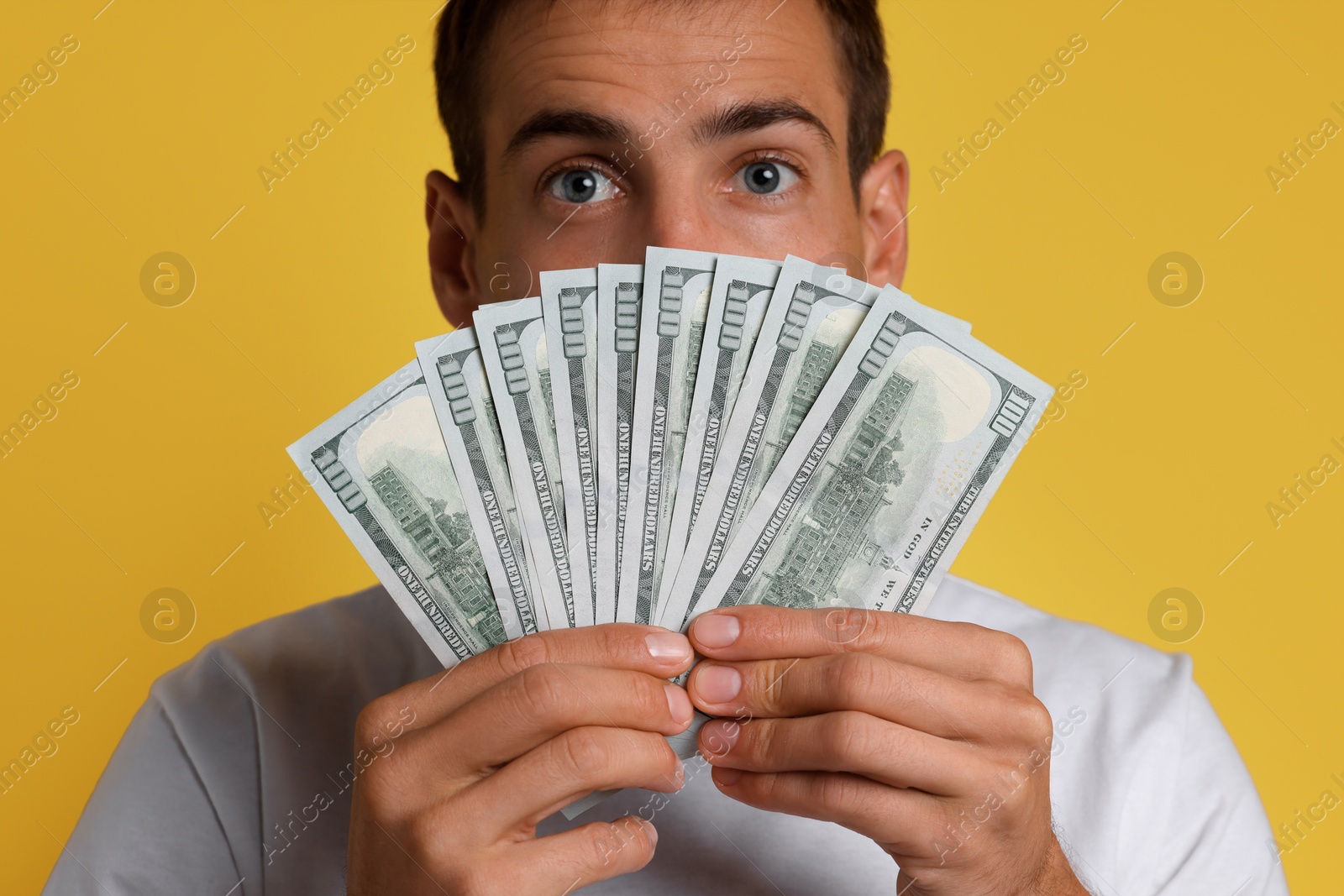 Photo of Man with dollar banknotes on yellow background