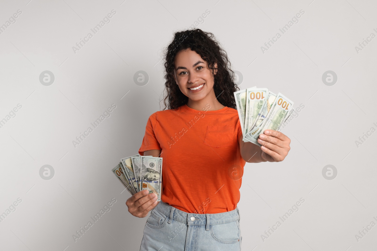 Photo of Happy woman with dollar banknotes on light grey background