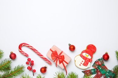 Photo of Flat lay composition with Christmas decor, gift box and delicious cookie in shape of snowman on white background, space for text