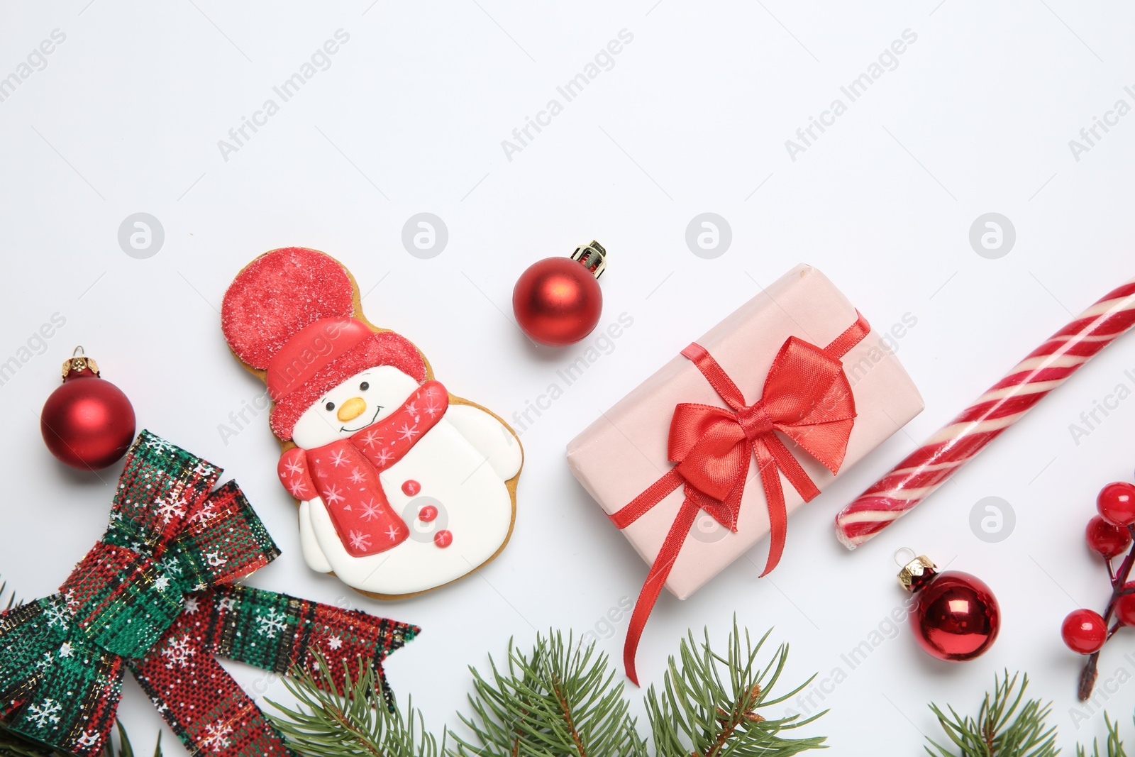 Photo of Flat lay composition with Christmas decor, gift box and delicious cookie in shape of snowman on white background