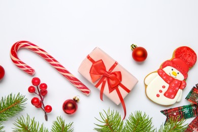 Photo of Flat lay composition with Christmas decor, gift box and delicious cookie in shape of snowman on white background