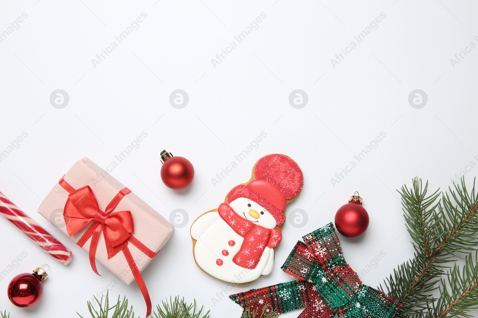 Photo of Delicious cookie in shape of snowman, candy and Christmas decor on white background, flat lay. Space for text