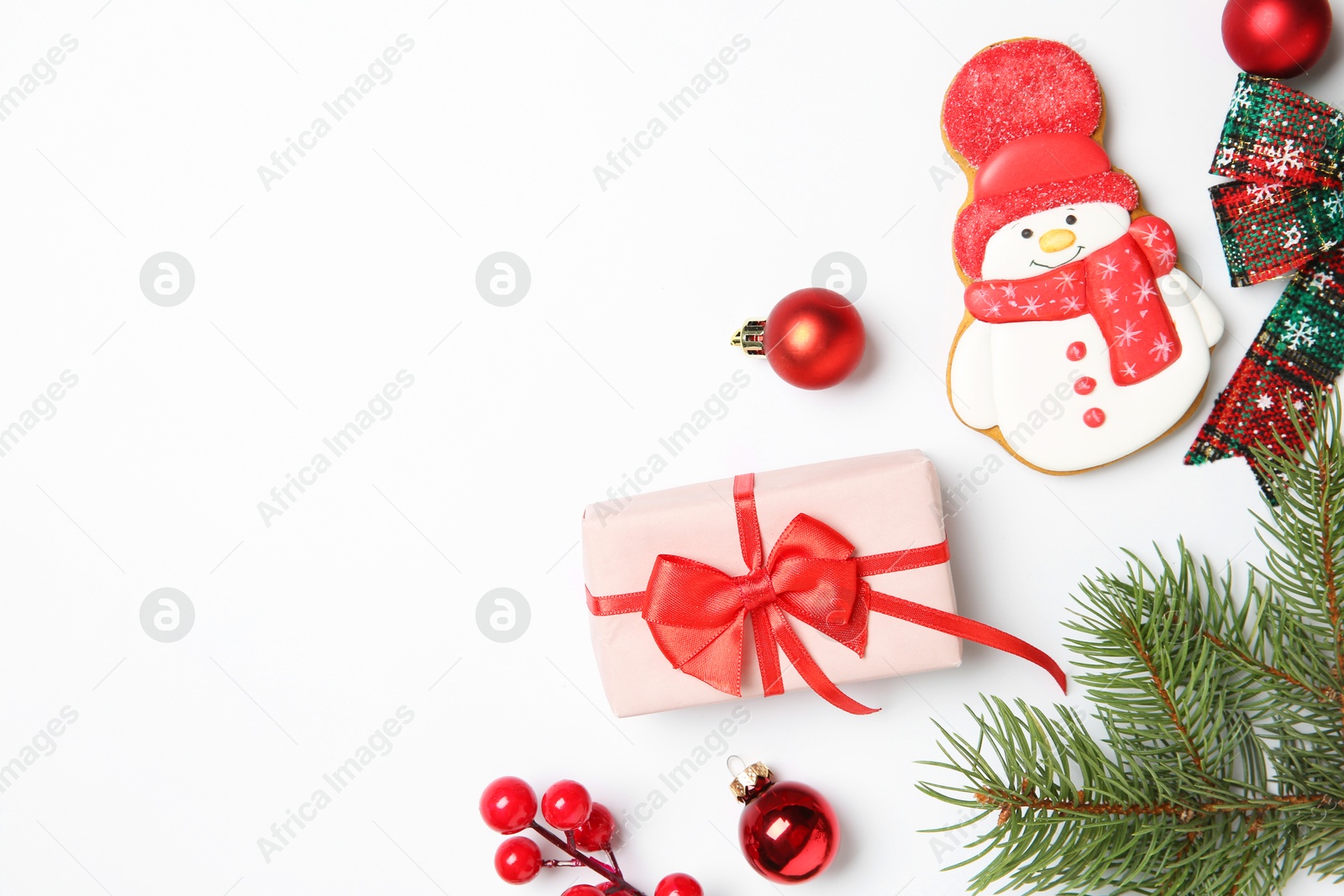 Photo of Flat lay composition with Christmas decor, gift box and delicious cookie in shape of snowman on white background, space for text