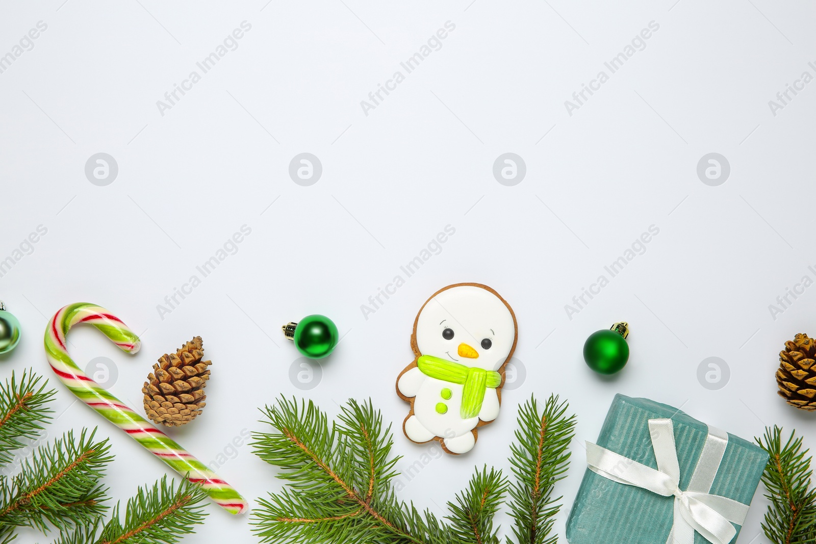 Photo of Flat lay composition with Christmas decor and delicious cookie in shape of snowman on white background, space for text