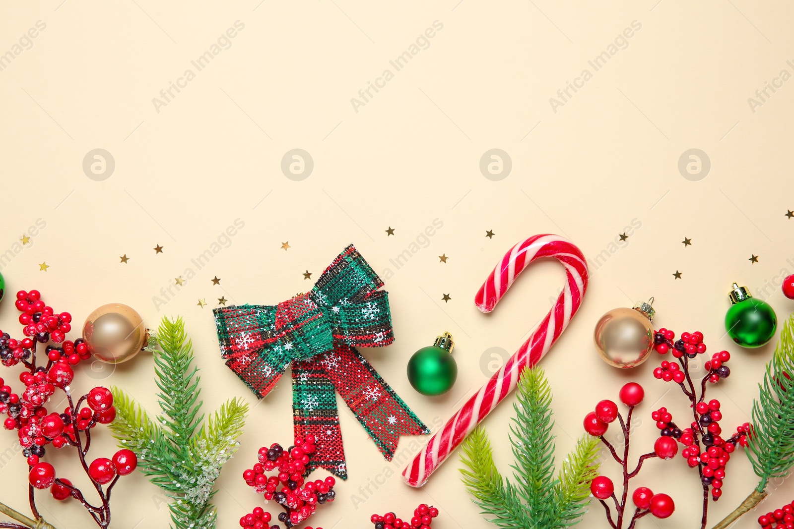 Photo of Flat lay composition with Christmas decor and candy cane on beige background, space for text