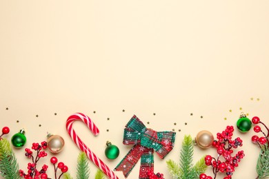 Photo of Flat lay composition with Christmas decor and candy cane on beige background, space for text