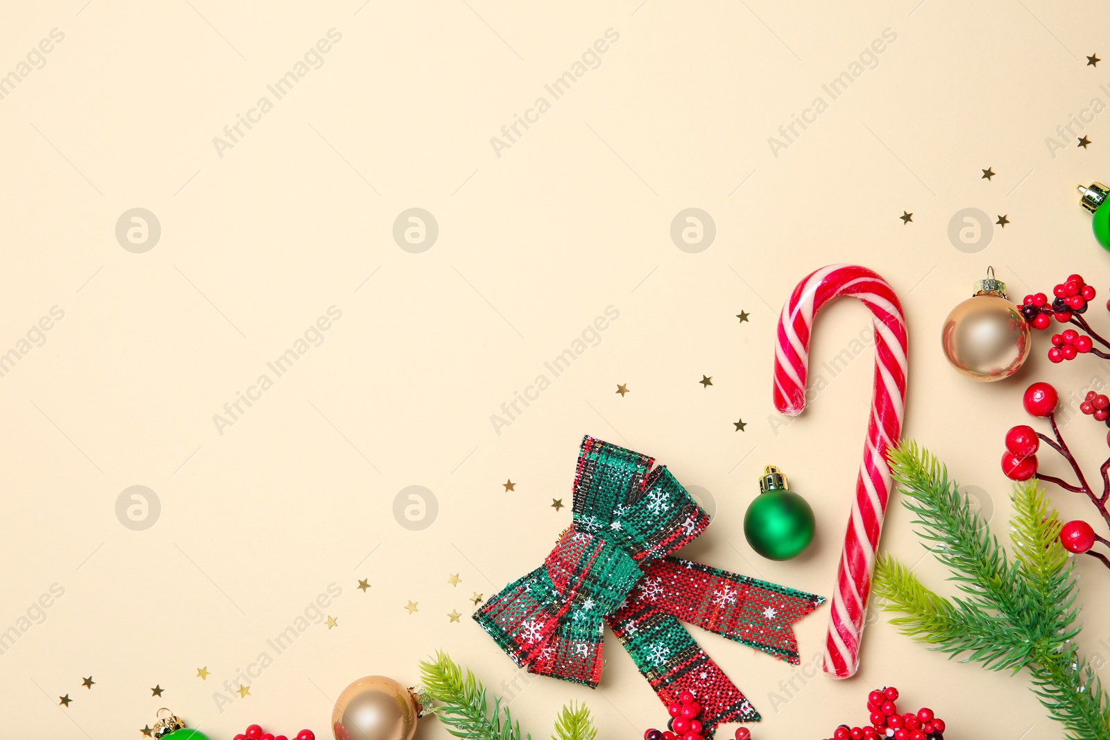 Photo of Flat lay composition with Christmas decor and candy cane on beige background, space for text