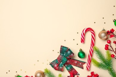 Photo of Flat lay composition with Christmas decor and candy cane on beige background, space for text