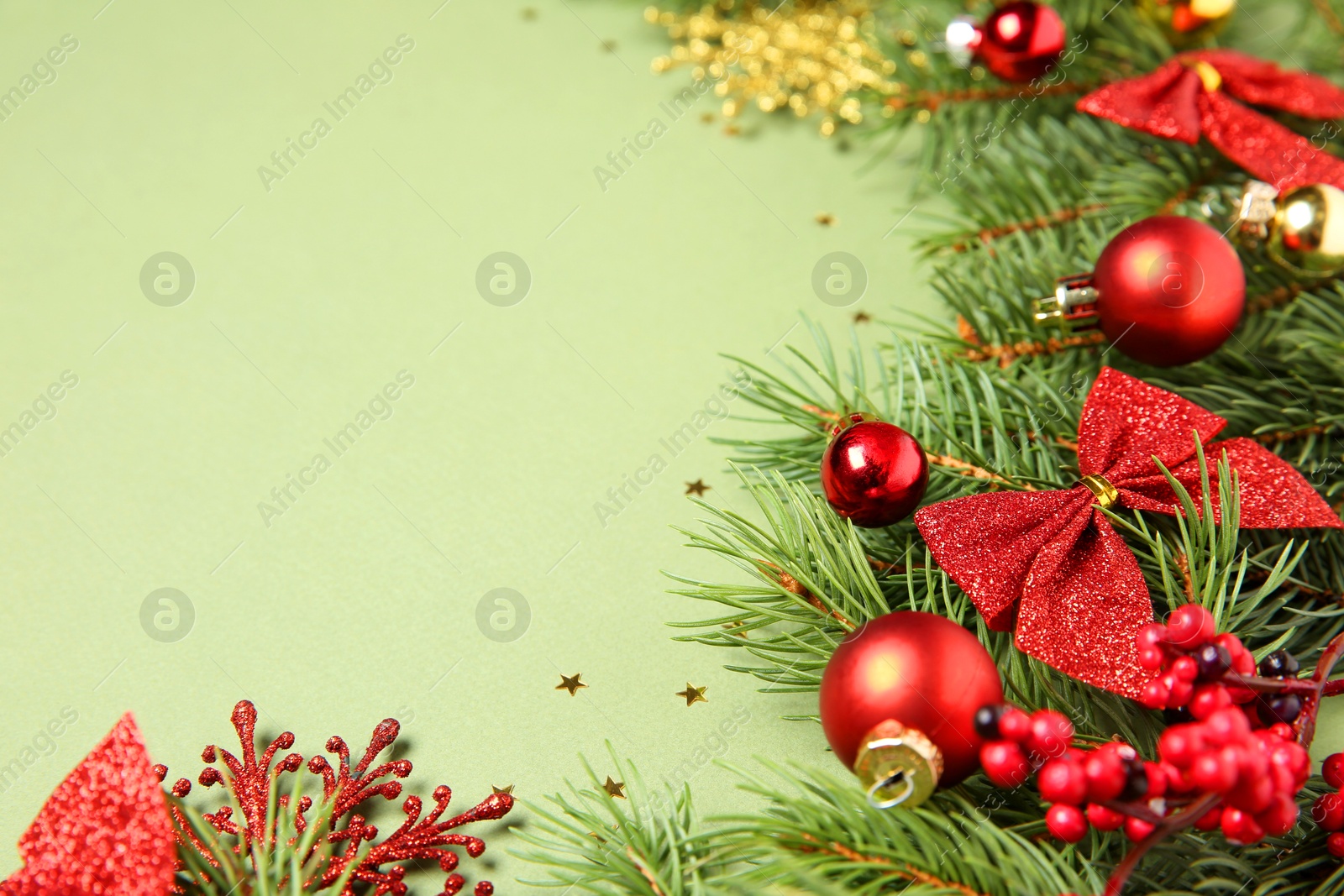 Photo of Christmas decor and fir tree branches on green background, closeup. Space for text