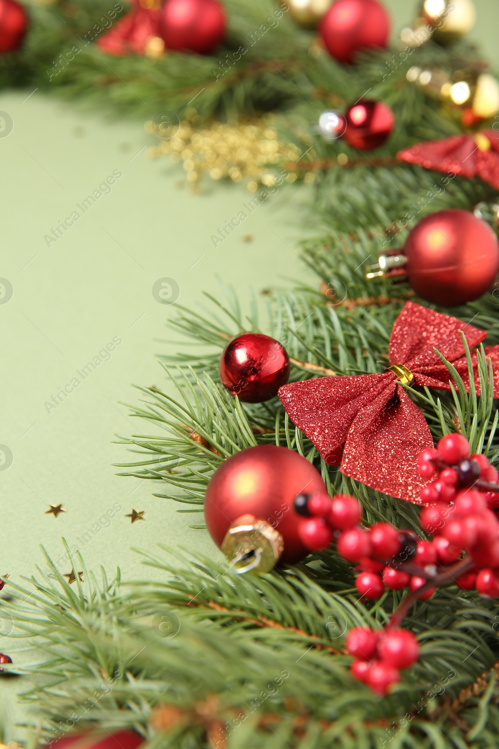 Photo of Christmas decor and fir tree branches on green background, closeup. Space for text