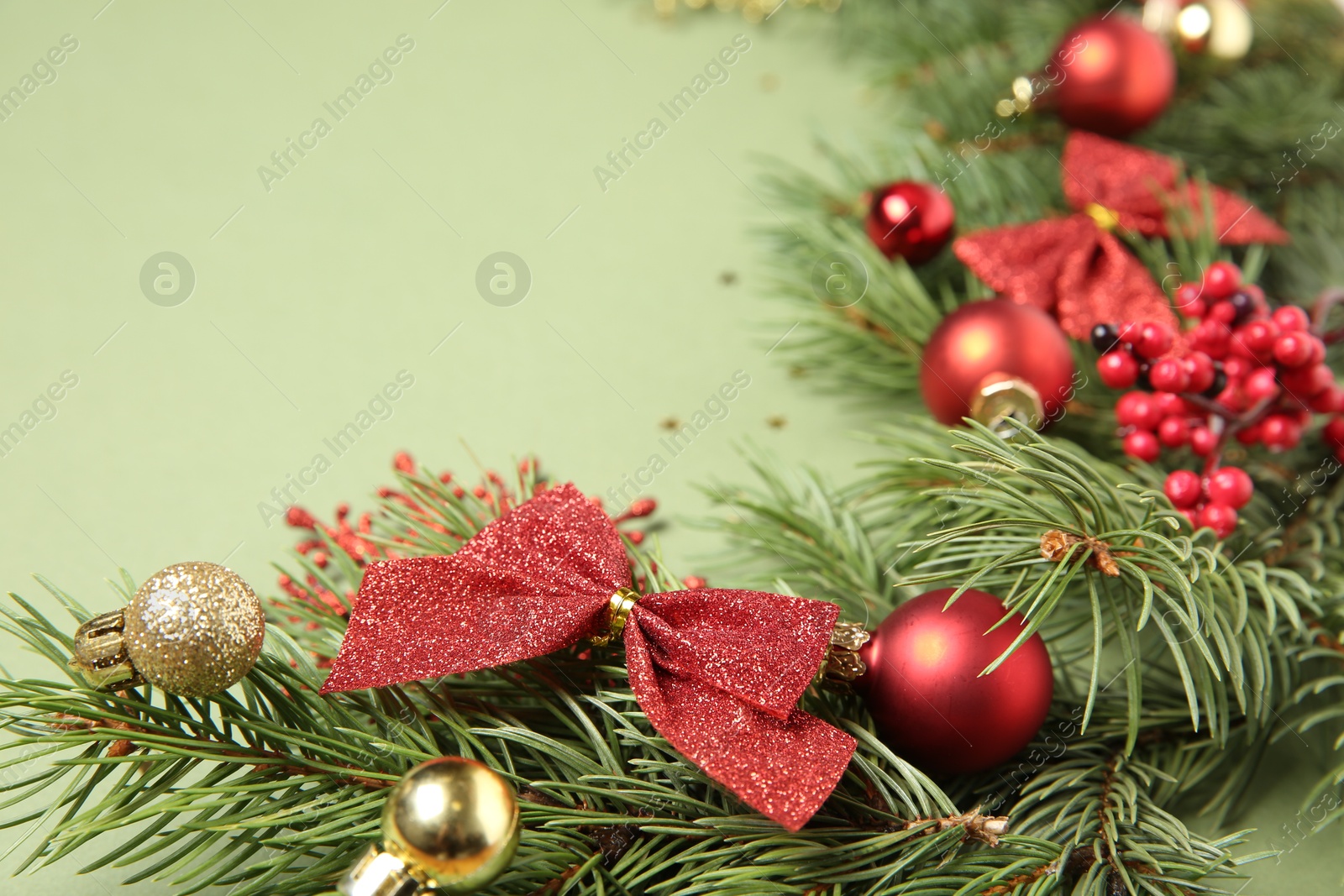 Photo of Christmas decor and fir tree branches on green background, closeup. Space for text