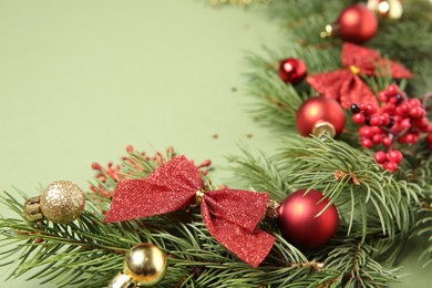 Photo of Christmas decor and fir tree branches on green background, closeup. Space for text