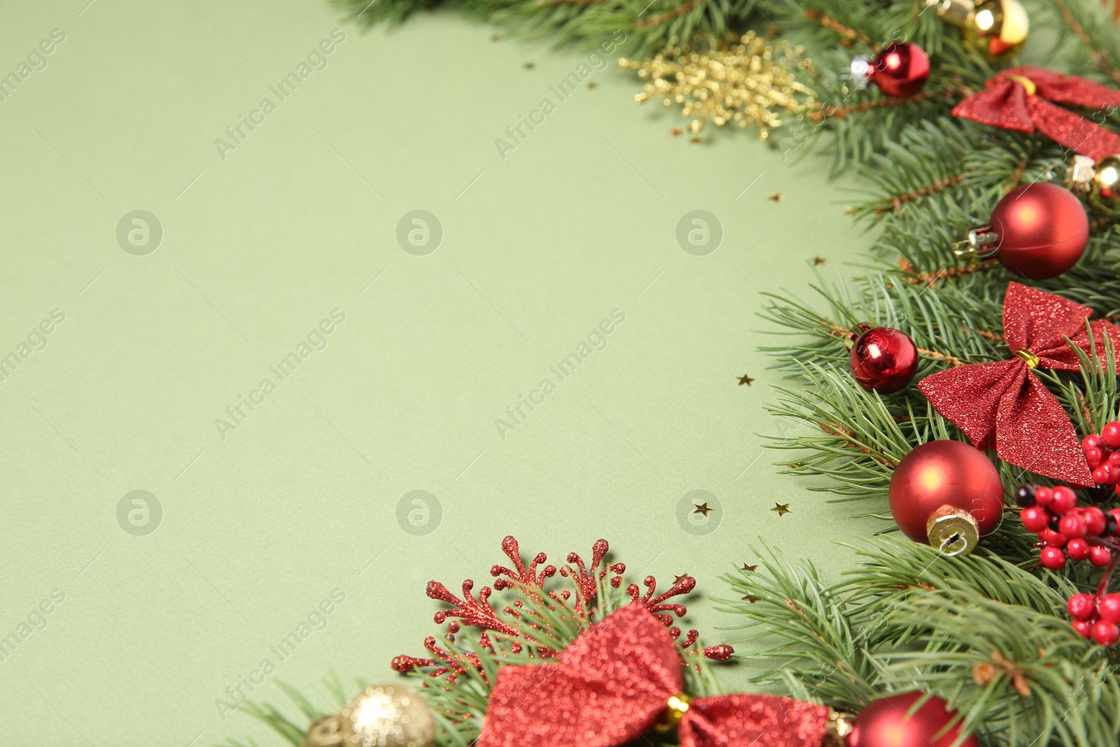 Photo of Christmas decor and fir tree branches on green background, closeup. Space for text