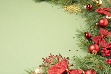 Photo of Christmas decor and fir tree branches on green background, closeup. Space for text