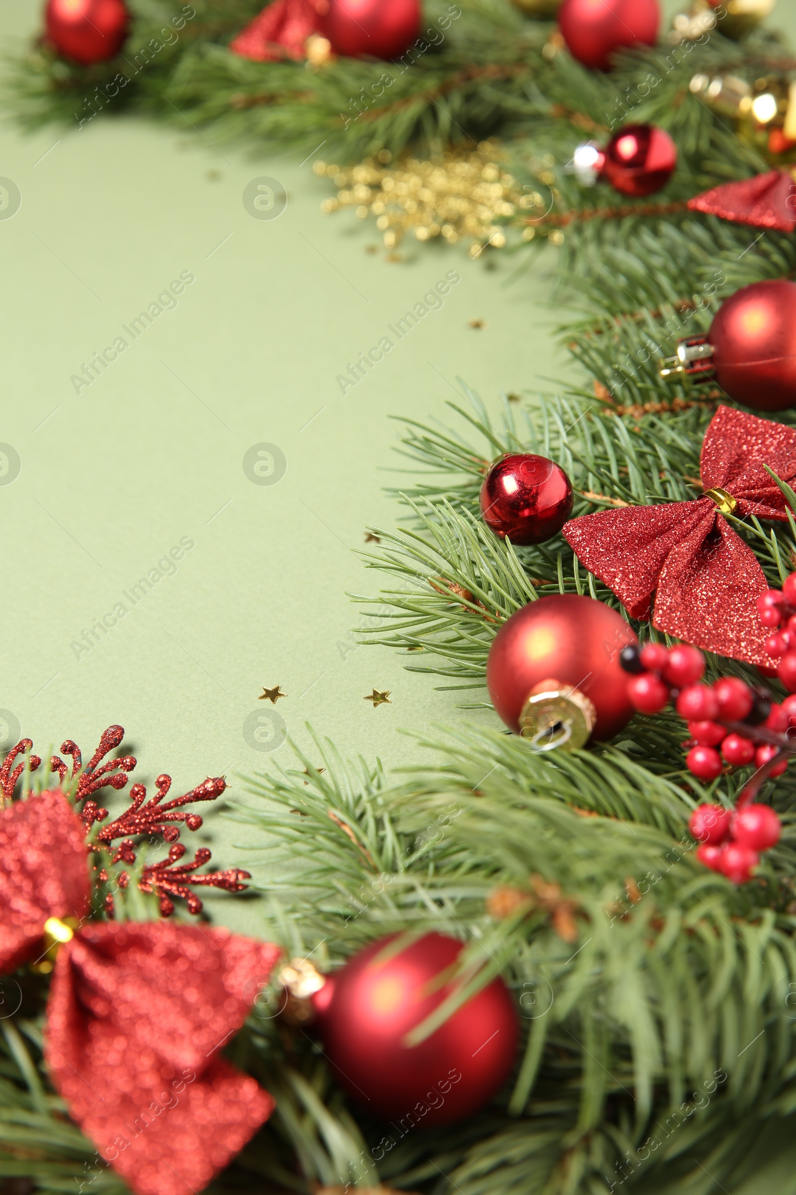 Photo of Christmas decor and fir tree branches on green background, closeup. Space for text