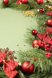 Photo of Christmas decor and fir tree branches on green background, closeup. Space for text