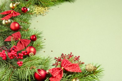 Photo of Christmas decor and fir tree branches on green background, closeup. Space for text