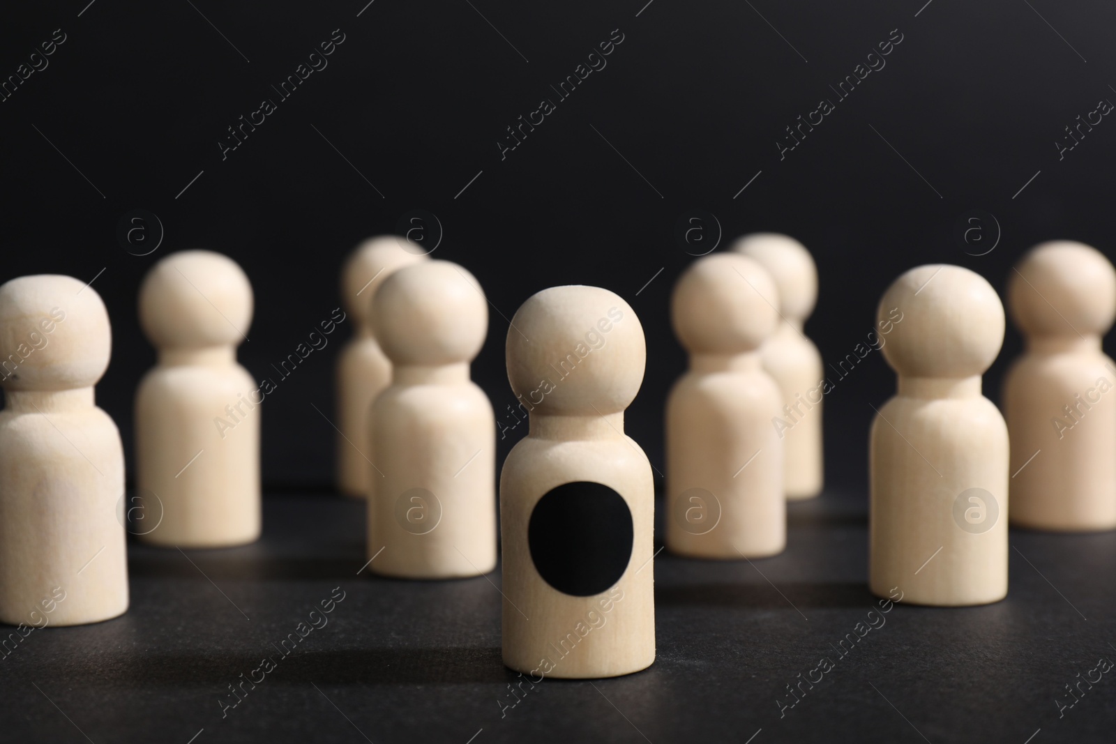 Photo of Winner. Piece with dark dot among wooden ones against black background, selective focus