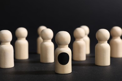 Photo of Winner. Piece with dark dot among wooden ones against black background, selective focus