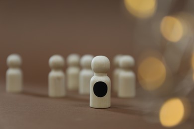 Photo of Winner. Piece with black dot among wooden ones on light brown background, selective focus