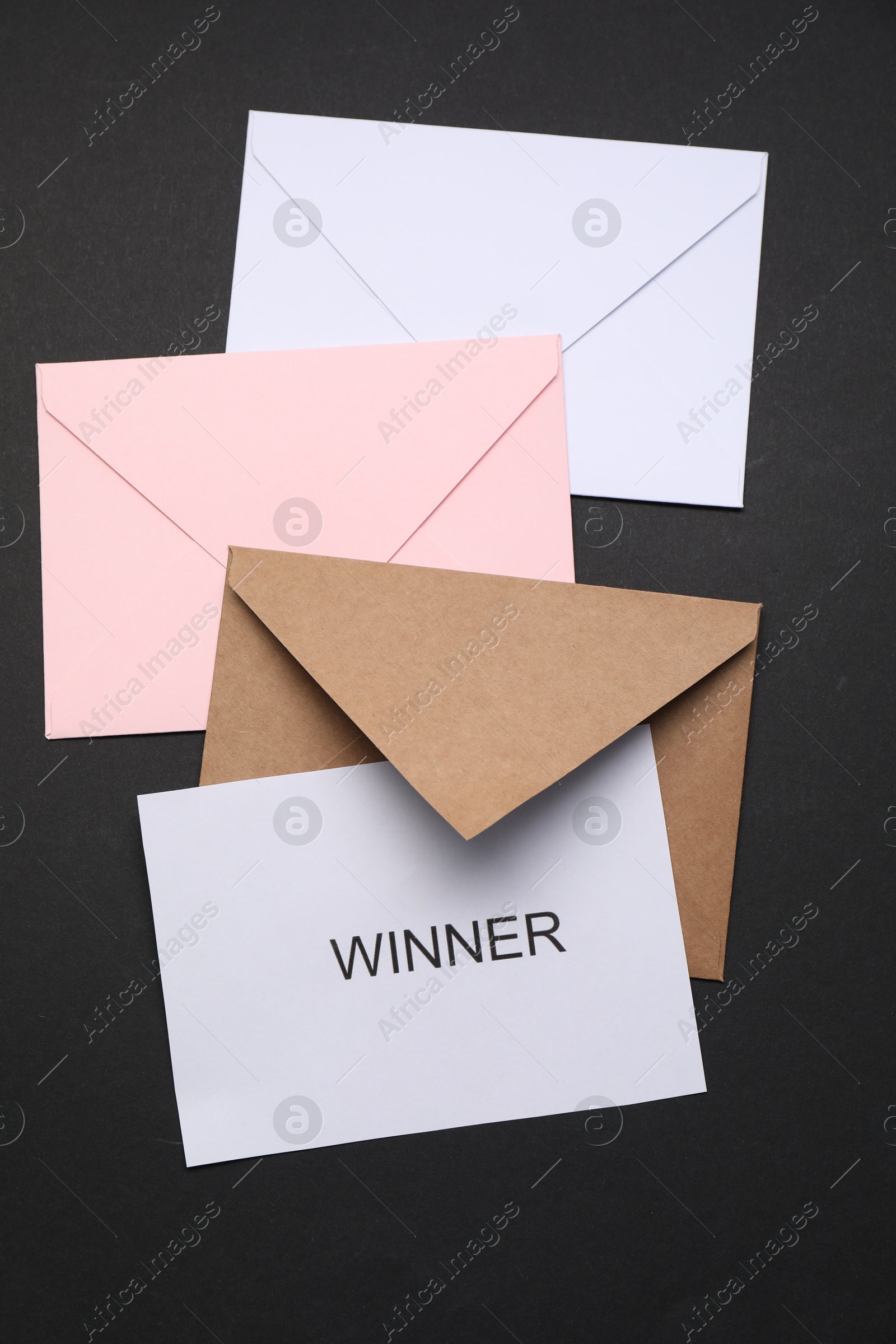 Photo of Card with word Winner and envelops on black background, flat lay