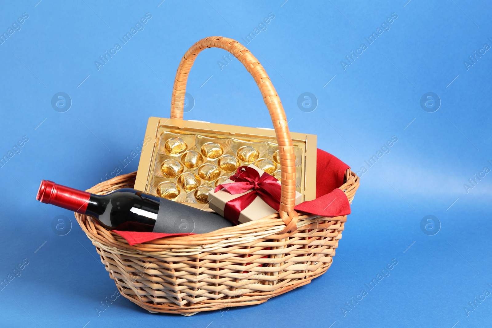 Photo of Wicker gift basket with wine on blue background