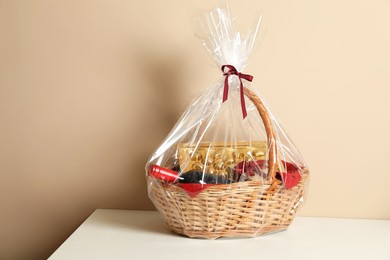 Photo of Wicker gift basket on table against beige background