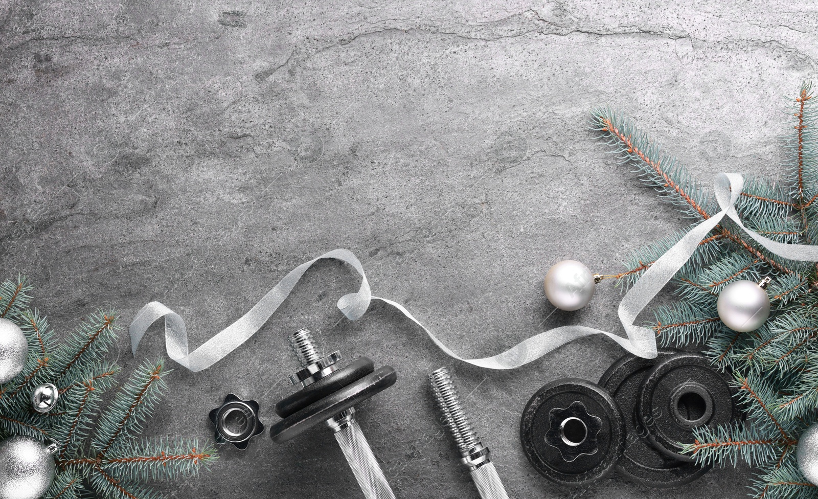 Photo of Barbell, dumbbell parts and Christmas decor on grey background, flat lay. Space for text