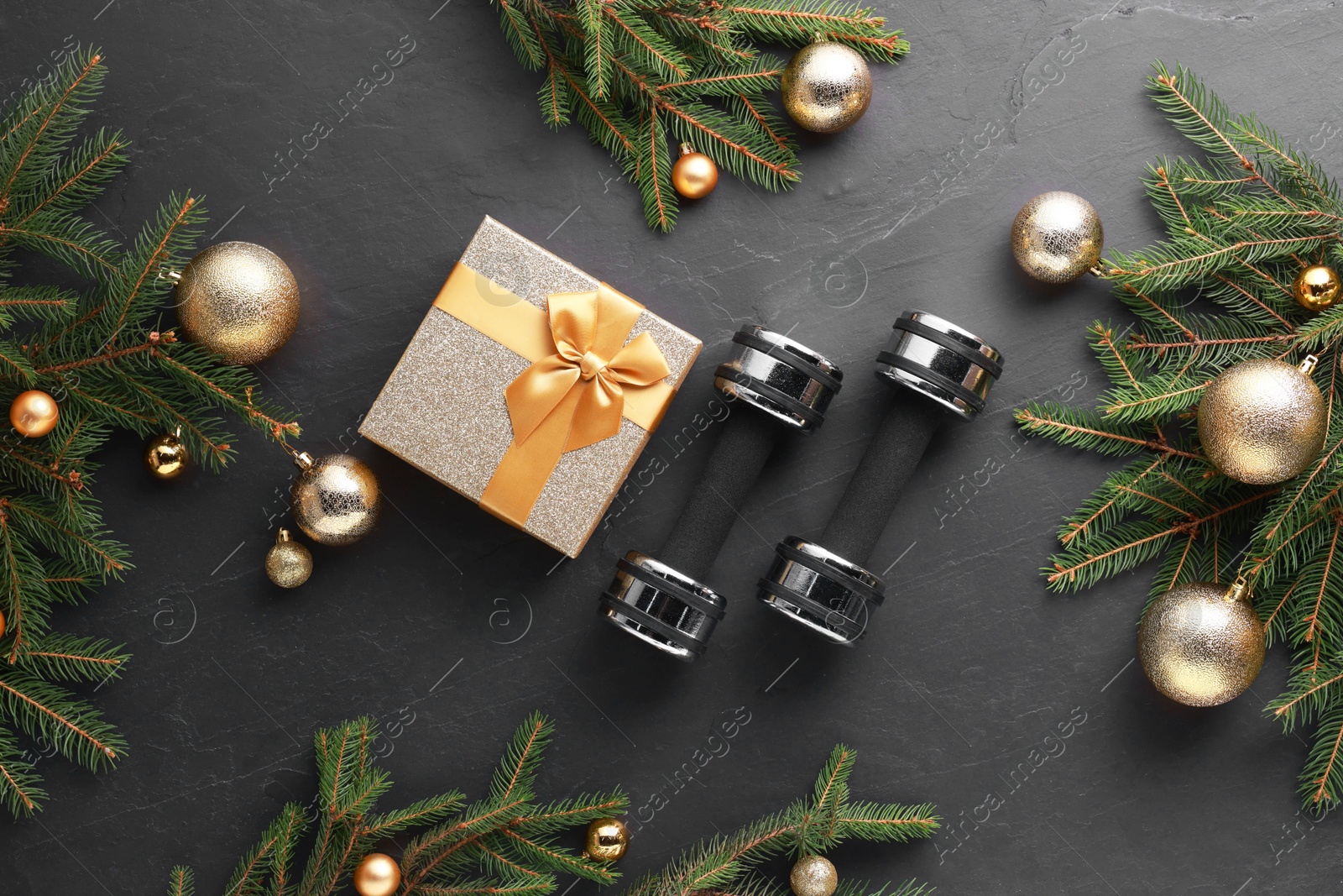 Photo of Dumbbells, gift box and Christmas decor on black background, flat lay