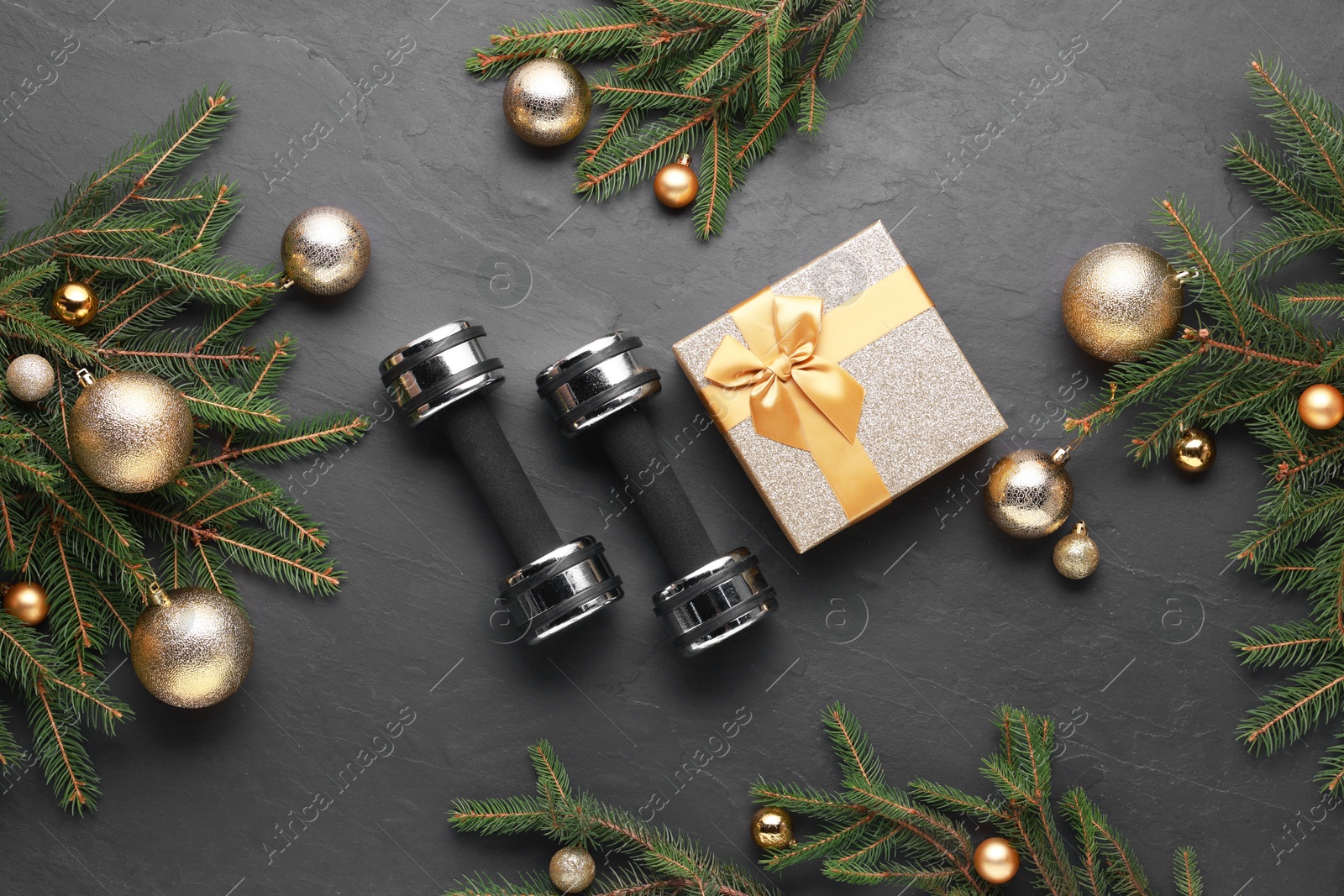 Photo of Dumbbells, gift box and Christmas decor on black background, flat lay