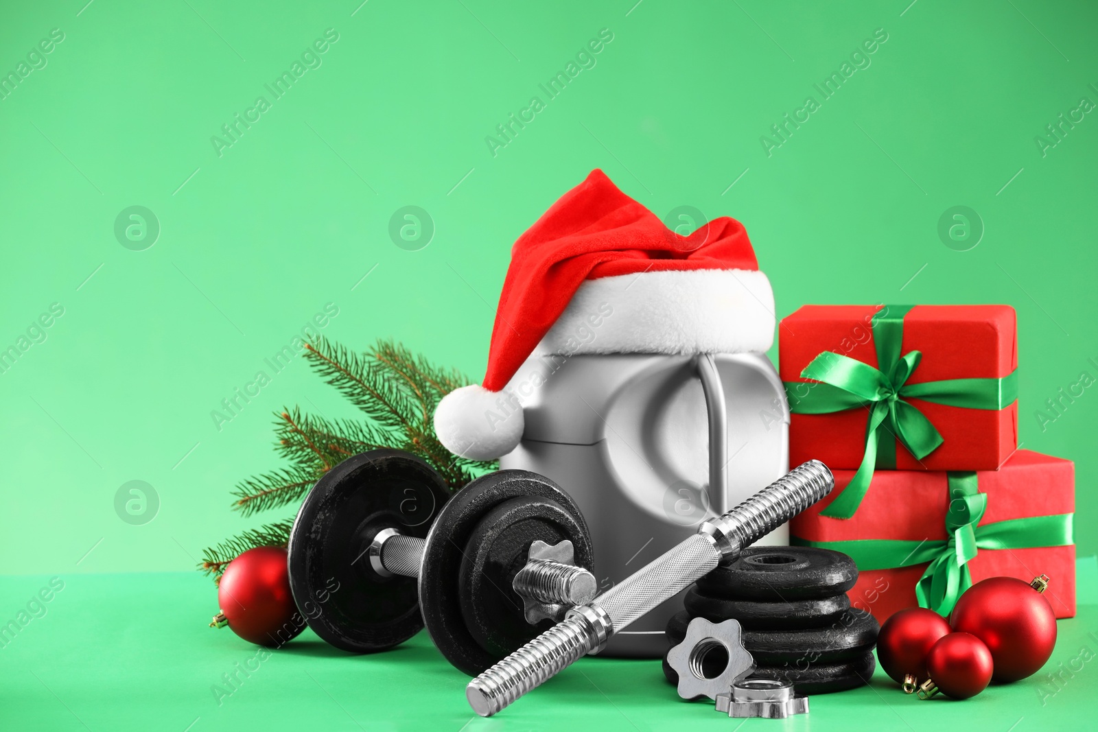 Photo of Dumbbells, container with supplement and Christmas decor on green background. Space for text