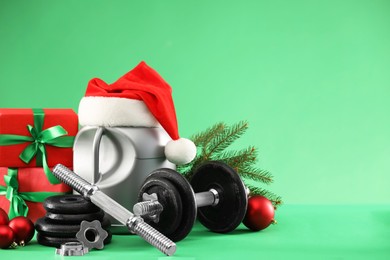 Photo of Dumbbells, container with supplement and Christmas decor on green background. Space for text