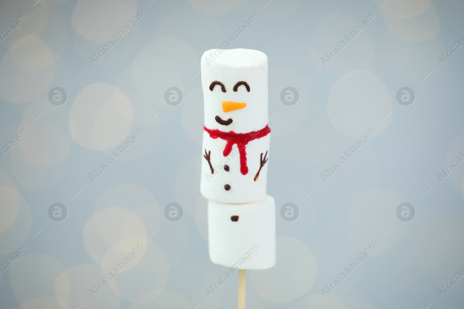 Photo of Funny snowman made of marshmallows on light background with blurred lights