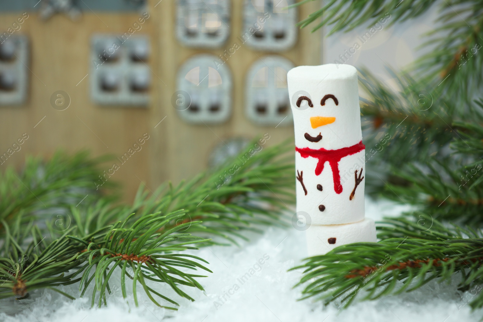 Photo of Funny snowman made with marshmallows and fir tree branches on artificial snow, closeup