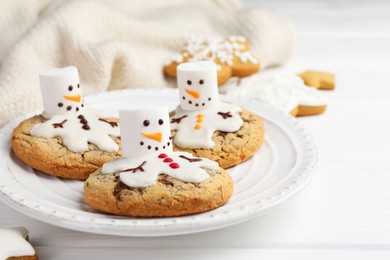 Photo of Delicious cookies with snowmen made of marshmallows on white table, closeup