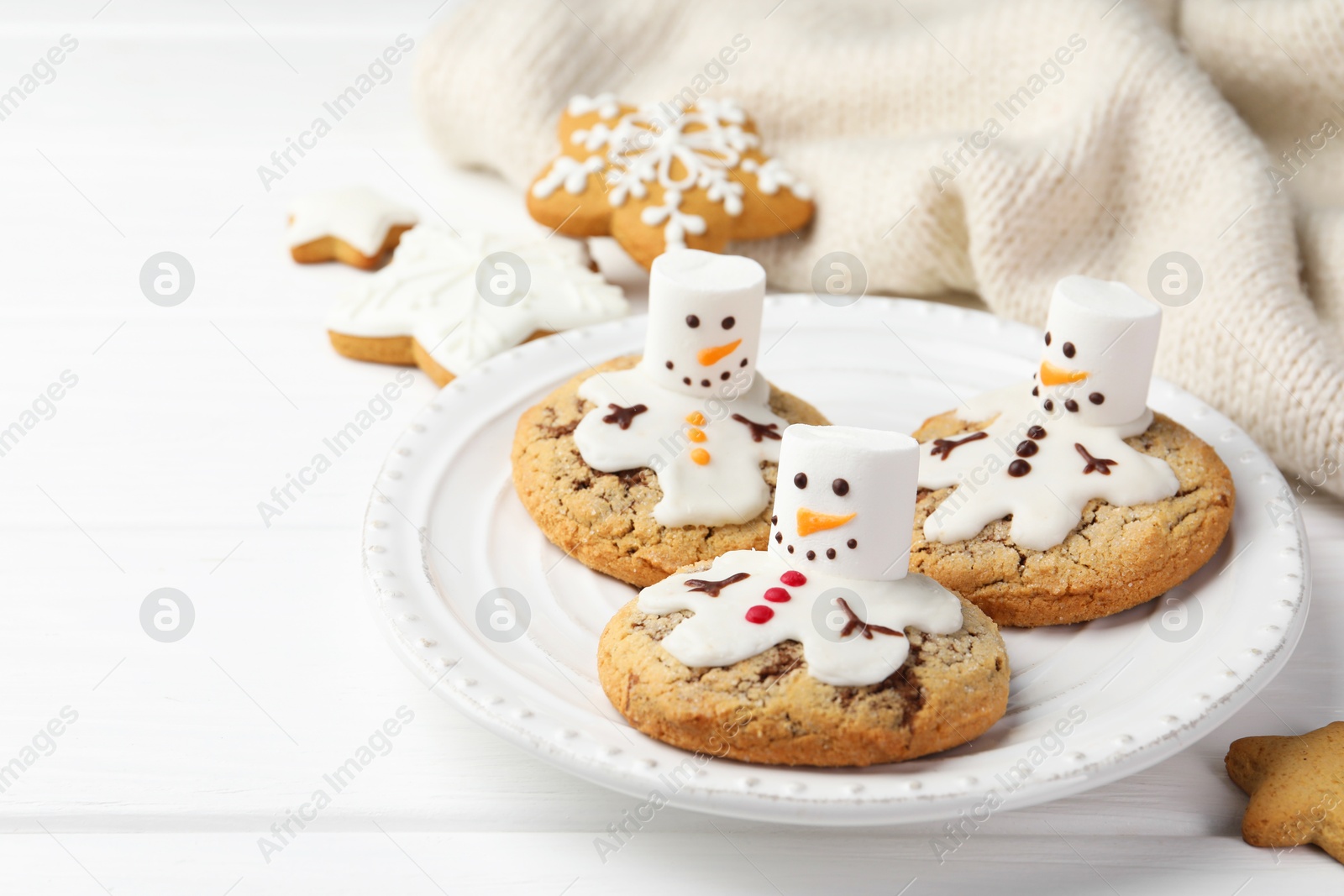 Photo of Delicious cookies with snowmen made of marshmallows on white table, closeup