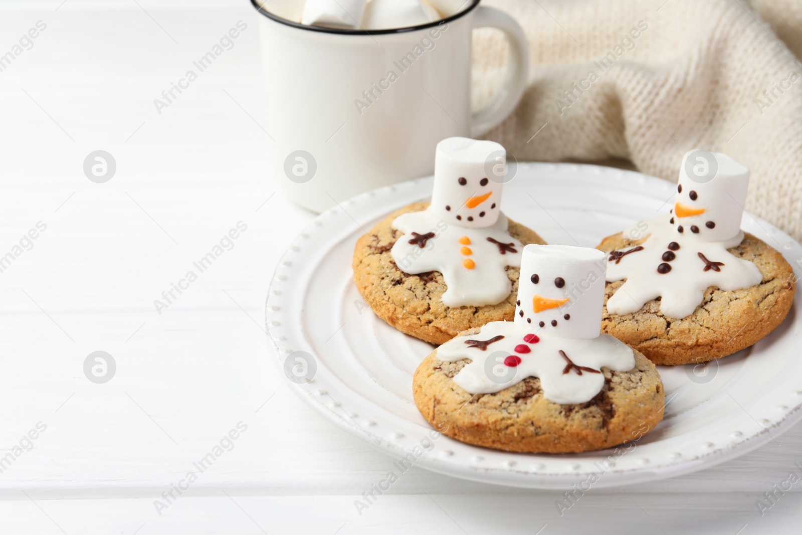 Photo of Delicious cookies with snowmen made of marshmallows on white table, closeup. Space for text