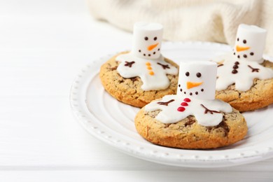 Photo of Delicious cookies with snowmen made of marshmallows on white table, closeup. Space for text