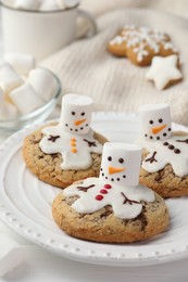 Photo of Delicious cookies with snowmen made of marshmallows on white table, closeup