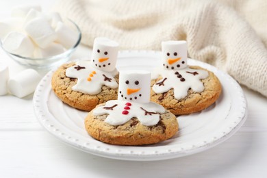 Photo of Delicious cookies with snowmen made of marshmallows on white table, closeup