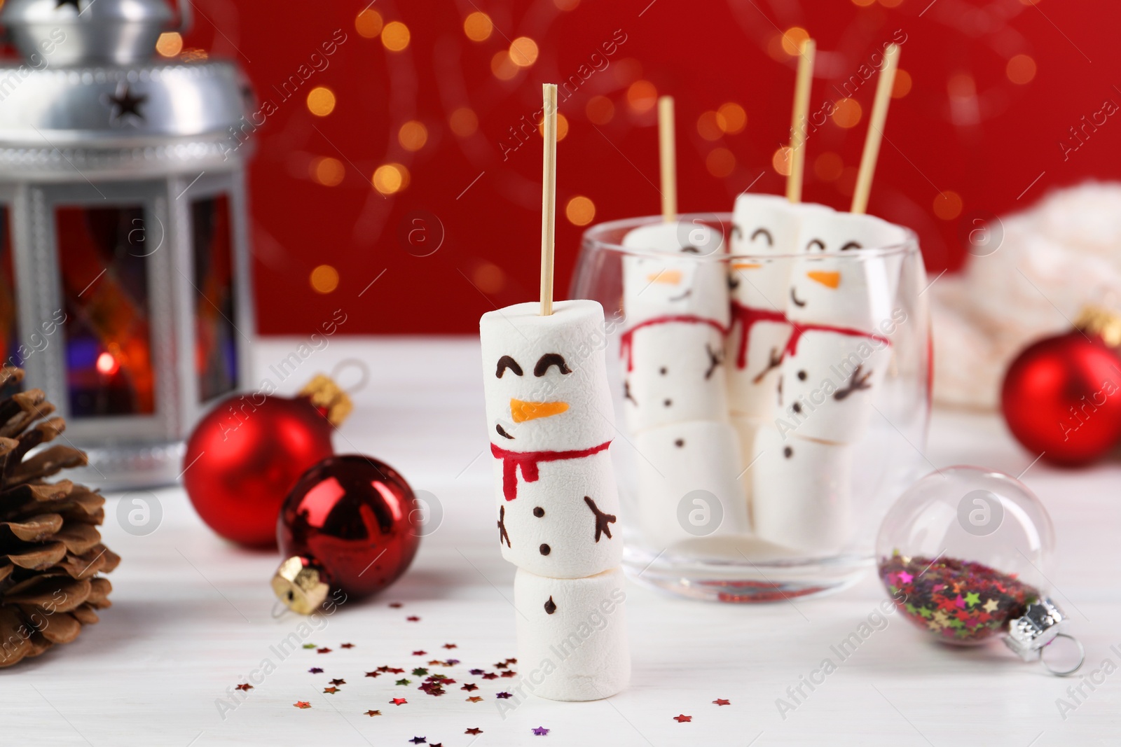 Photo of Funny snowmen made with marshmallows and Christmas decor on white wooden table, selective focus