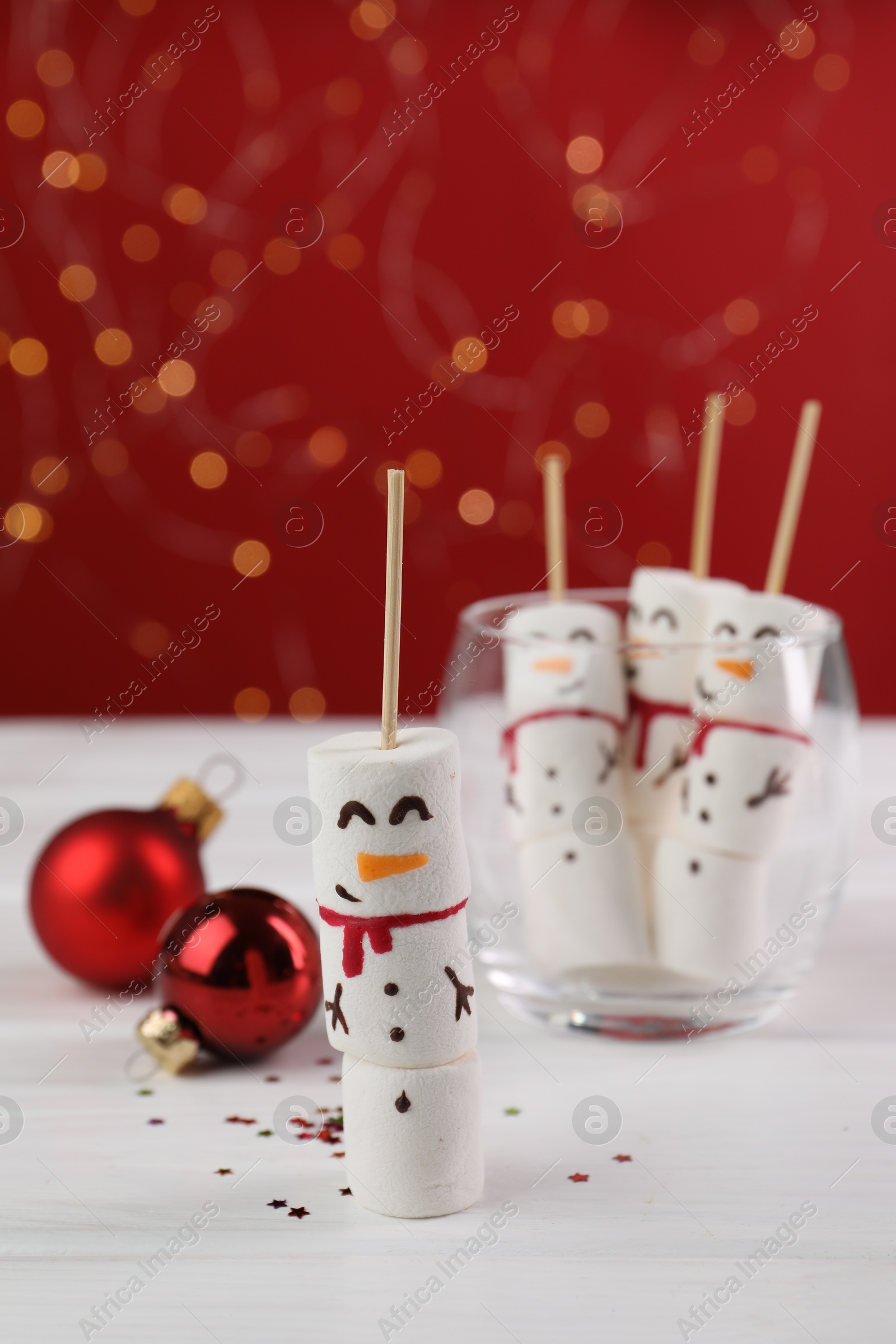 Photo of Funny snowmen made with marshmallows and Christmas decor on white wooden table, selective focus