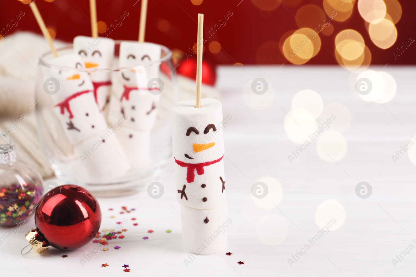 Photo of Funny snowmen made with marshmallows and Christmas decor on white wooden table, selective focus