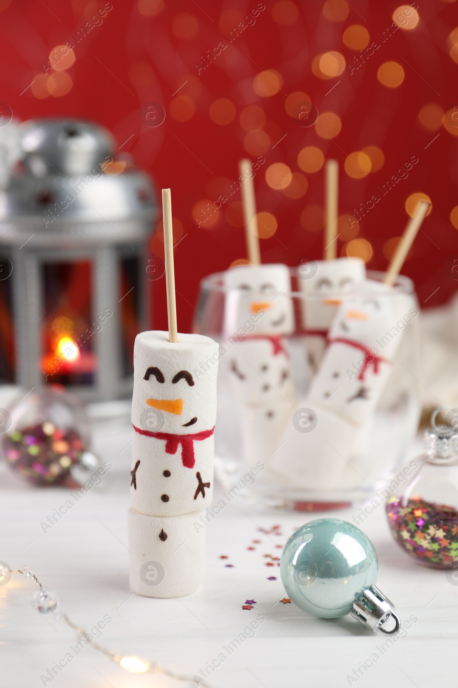 Photo of Funny snowmen made with marshmallows and Christmas decor on white table, selective focus