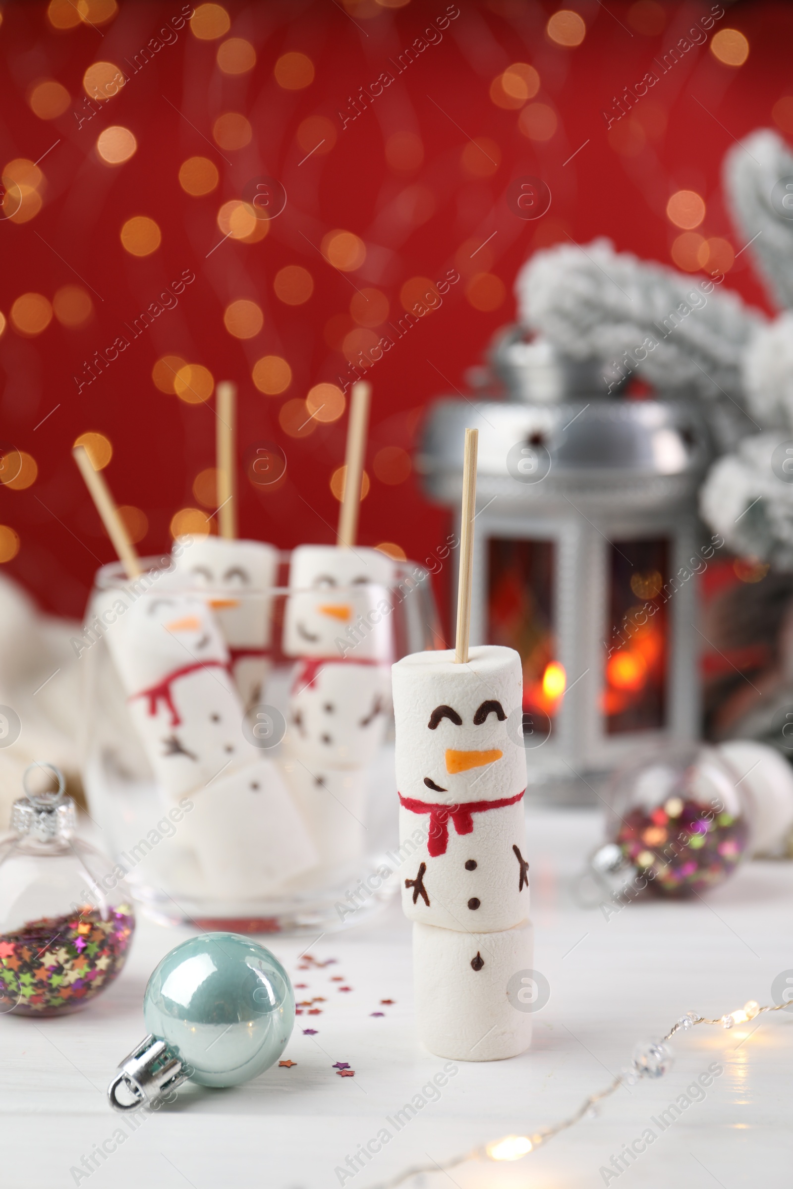 Photo of Funny snowmen made with marshmallows and Christmas decor on white table, selective focus